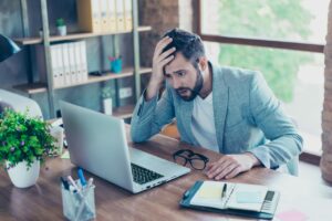 Homme devant son ordinateur se tenant la tête avec la main